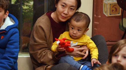 An adult holding a young child during a family activity at Lanhydrock. The child is holding a small red soft toy.